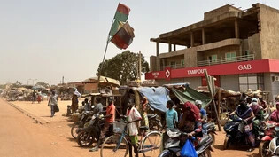 ARCHIV - Menschen stehen auf der Straße eines Vororts der burkinischen Hauptstadt Ouagadougou. Foto: Christina Peters/dpa-Zentralbild/dpa